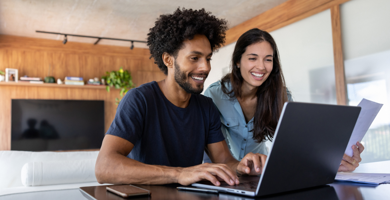 Imagem de casal feliz pagando boleto para quitar financiamento